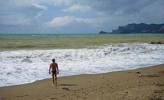 sudak, Crimea-25 settembre 2014-paesaggio marino con bellissime onde color smeraldo e un uomo sulla riva. foto