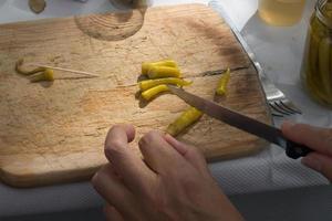 mani di donna irriconoscibili che tagliano i peperoncini verdi su un tavolo di legno. preparare la tapa spagnola foto