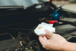 il meccanico di auto sta controllando l'olio motore dell'auto usando un acciaio e un detergente per tessuto. foto