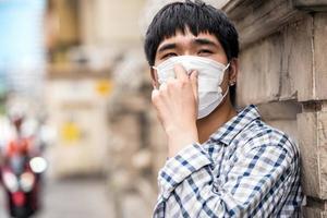 giovane uomo asiatico che indossa una maschera per il viso all'aperto in città durante la pandemia covid-19 foto