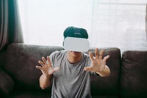 giovane uomo asiatico che indossa occhiali per realtà virtuale in soggiorno per ammirare la realtà virtuale. foto