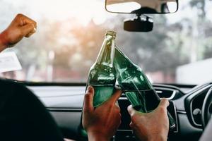 due amici maschi stanno festeggiando in macchina mentre fanno tintinnare insieme una bottiglia di birra. foto