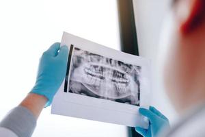 dentisti maschi asiatici stanno analizzando le immagini a raggi X dei pazienti in laboratorio. foto