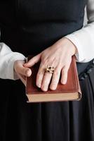 libro strappato antico con le mani di una giovane donna tenuta contro il vestito nero. copia, spazio vuoto per il testo foto