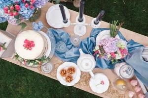 tavolo da dessert per banchetto decorato in stile rustico decorato con piatti, posate, bicchieri, candele e composizioni floreali. vista dall'alto. copia, spazio vuoto per il testo foto