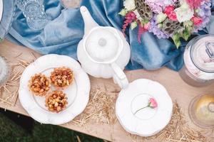 tavolo da dessert per banchetto decorato con piatti, posate, bicchieri, teiera in ceramica e composizioni floreali. vista dall'alto. copia, spazio vuoto per il testo foto