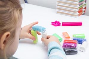 la ragazza al tavolo sta giocando con la pasta da modellare. giochi per bambini per la motricità fine foto