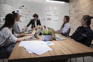 incontro di un team di professionisti, colleghi multirazziali e colleghi di lavoro e presentazione nella sala conferenze dell'ufficio commerciale con un manager maschio caucasico, discutendo di finanza e marketing. foto