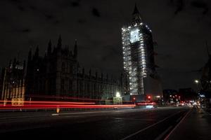 il palazzo di Westminster e il Big Ben illuminato di notte con una scia di luci foto