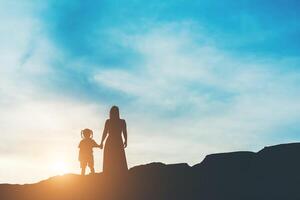 silhouette di madre con sua figlia in piedi e tramonto foto