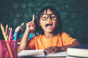 bambina premurosa con libro vicino a un consiglio scolastico foto