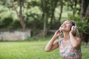 donna asiatica che ascolta la musica preferita sulle cuffie. tempo felice e relax. foto