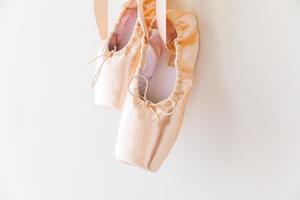 nuove scarpe da ballo beige pastello con nastro di raso isolato su sfondo bianco. ballerine classiche da punta per allenamento di danza. concetto di scuola di danza classica, spazio di copia foto