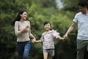 la famiglia felice si diverte madre, padre e figlia corrono nel parco. foto