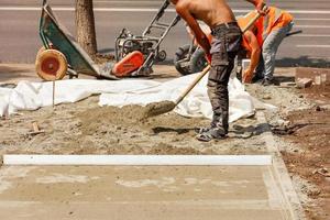 i lavoratori delle utility preparano un sito per la posa di lastre di pavimentazione in una giornata estiva. foto