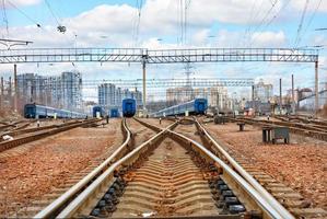 una vasta rete di binari ferroviari sullo sfondo di un cielo nuvoloso blu e un paesaggio cittadino sfocato. foto