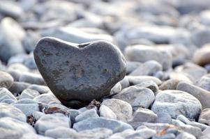 pietra a forma di cuore sullo sfondo della spiaggia. giornata di sole estivo. concetto di amore, matrimonio e San Valentino. trovare pietre belle e interessanti. vacanza al mare foto