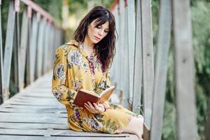 giovane donna che legge un libro su un ponte rurale. foto