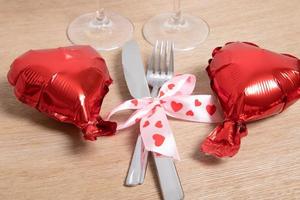 posate e bicchieri con palloncino rosso a forma di cuore. tavola decorata per una romantica cena di San Valentino foto