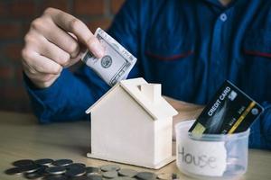 gli uomini usano le banconote nel salvadanaio di casa con l'idea di raccogliere soldi per comprare una nuova casa. foto