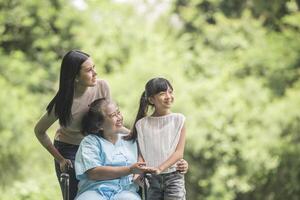 nonna felice in sedia a rotelle con sua figlia e suo nipote in un parco, vita felice tempo felice. foto