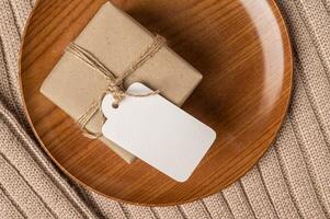 confezione regalo sul piatto di legno e maglione con etichetta trasparente foto