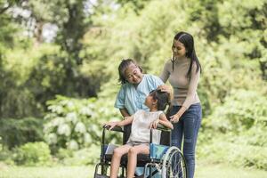 nonna felice in sedia a rotelle con sua figlia e suo nipote in un parco, vita felice tempo felice. foto