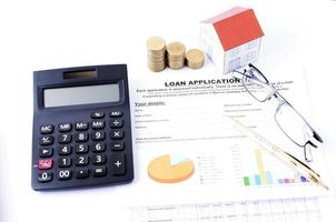 modulo di domanda di prestito e pila di monete di denaro e calcolatrice e carta domestica per il concetto di mutui ipotecari foto
