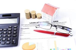 concetto di prestiti ipotecari con modulo di domanda di prestito e pila di monete e carta domestica e occhiali e penna rossa con calcolatrice foto