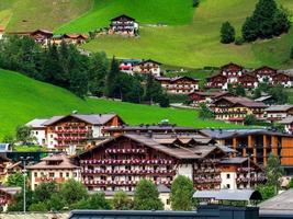 verdi colline di una località alpina in austria in estate. piccolo villaggio, hotel e chalet, tutti a colori. belle terrazze e pannelli solari sui tetti. la vicinanza della civiltà e della natura pura. foto