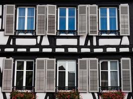 classiche finestre alsaziane in una casa a graticcio, decorate con intagli in legno e fiori foto