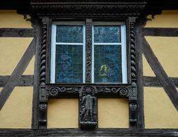 classiche finestre alsaziane in una casa a graticcio, decorate con intagli in legno e fiori foto