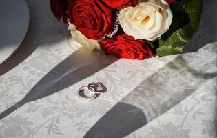 preziose fedi nuziali e bouquet da sposa. fotografia pubblicitaria di matrimonio. foto