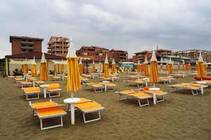 lettini allineati su una spiaggia deserta in una giornata nuvolosa. Toscana foto