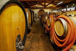botti di rovere di vino nel seminterrato di un enologo italiano. vecchia tecnologia di produzione del vino. foto
