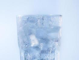 un bicchiere d'acqua limpida per bevande fredde. gocce di ghiaccio e acqua si aggrappano al bordo del bicchiere. soda con cubetti di ghiaccio foto