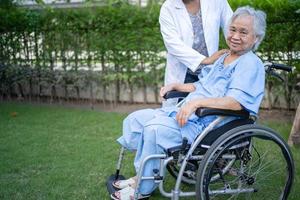 medico aiuto e cura asiatico anziano o anziana signora anziana paziente seduta su sedia a rotelle al parco nel reparto ospedaliero di cura, concetto medico sano e forte. foto