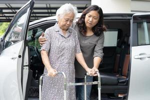 aiutare e sostenere la donna anziana o anziana asiatica anziana paziente a piedi con walker prepararsi a raggiungere la sua auto, concetto medico sano e forte. foto