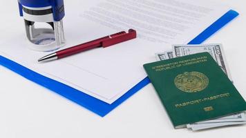 passaporto dell'uzbekistan con dollari americani sullo sfondo di documenti e contratto. concetto - corruttore e corruzione foto