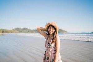 giovane donna asiatica che cammina sulla spiaggia. bella femmina felice rilassarsi camminando sulla spiaggia vicino al mare quando il tramonto in serata. le donne di stile di vita viaggiano sul concetto di spiaggia. foto