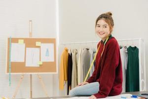 professionista bella asiatica stilista di moda femminile che lavora vestito di misurazione su un disegno di abbigliamento manichino in studio. concetto di lavoro delle donne di stile di vita. foto