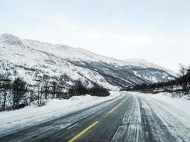 guidando attraverso la tempesta di neve di blizzard con ghiaccio nero sulla strada, norvegia. foto