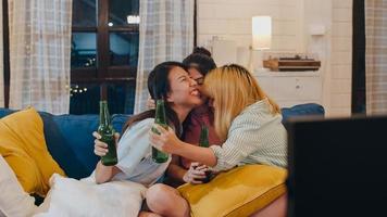 gruppo di donne asiatiche festa a casa, femmina che beve birra guardando la tv tifare calcio momento divertente insieme sul divano nel soggiorno di notte. adolescente giovane amico tifoso di calcio, celebra il concetto di vacanza. foto