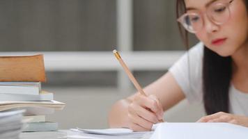 studentesse asiatiche che leggono libri in biblioteca all'università. giovane studentessa universitaria fa i compiti, legge libri di testo, studia duramente per la conoscenza e l'istruzione sulla scrivania del campus universitario. foto