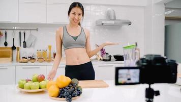 blogger sportiva donna asiatica che utilizza la videocamera che registra come fare il video del succo di mela per il suo abbonato, le donne usano frutta biologica che fa il succo di mela da sola a casa. concetto di cibo sano. foto