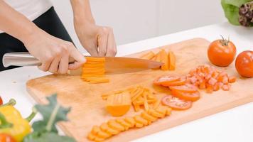 la donna asiatica felice ha tagliato un sacco di carota preparare l'ingrediente per fare il cibo in cucina, verdura biologica per uso femminile per cibo sano a casa. donne di stile di vita che fanno il concetto di cibo. foto