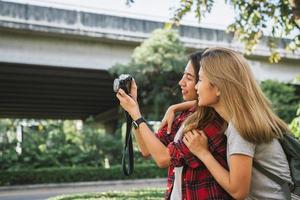 le donne asiatiche dell'amico del bello viaggiatore felice portano lo zaino. giovani donne asiatiche gioiose amiche che usano la fotocamera per fare foto durante il tour della città, emozioni allegre. stile di vita delle donne all'aperto nel concetto di città.