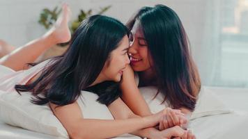 coppia di donne lesbiche asiatiche lgbtq che parlano sul letto a casa. giovane amante dell'asia femmina felice relax riposare insieme dopo il risveglio mentre si sdraia sul letto in camera da letto a casa al mattino concetto. foto