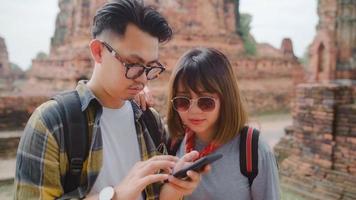 le coppie asiatiche del viaggiatore che usano lo smartphone per la direzione e guardano sulla mappa della posizione mentre trascorrono le vacanze ad ayutthaya, in tailandia, le coppie dolci dei viaggiatori con zaino e sacco a pelo si godono il viaggio nella città tradizionale. foto