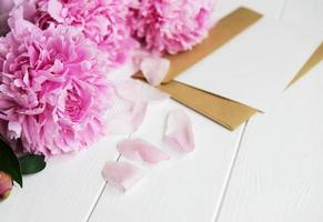 biglietto d'invito, busta artigianale e fiori di peonia rosa foto
